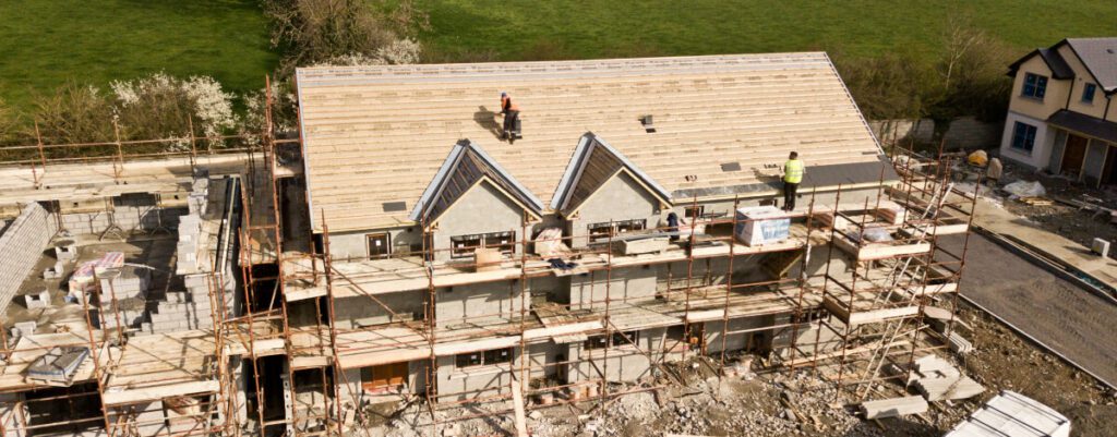 Aerial view of a house under construction with new roof sheathing and dormers Aerial view of a house under construction with new roof sheathing and dormers