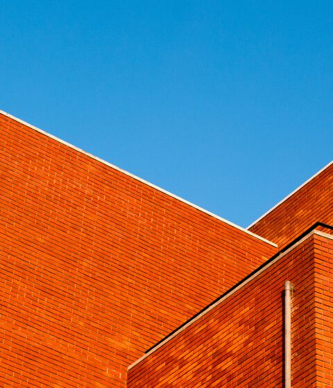 Orange brick commercial building roofline against a blue sky Orange brick commercial building roofline against a blue sky