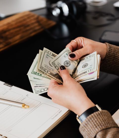 Person counting cash at a desk while budgeting for roof costs Person counting cash at a desk while budgeting for roof costs
