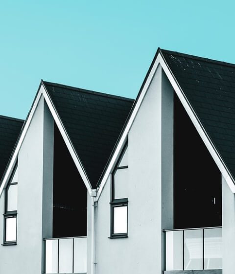 Modern gabled houses with dark roofs against a blue sky Modern gabled houses with dark roofs against a blue sky