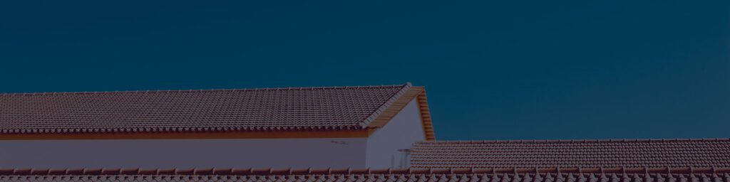 Red tile roofline against a deep blue evening sky