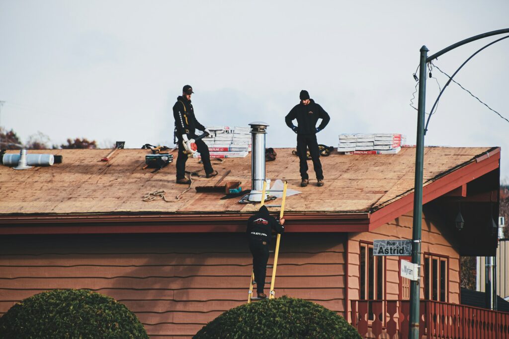 Roofing crew working on a low-slope roof above a brick home Roofing crew working on a low-slope roof above a brick home