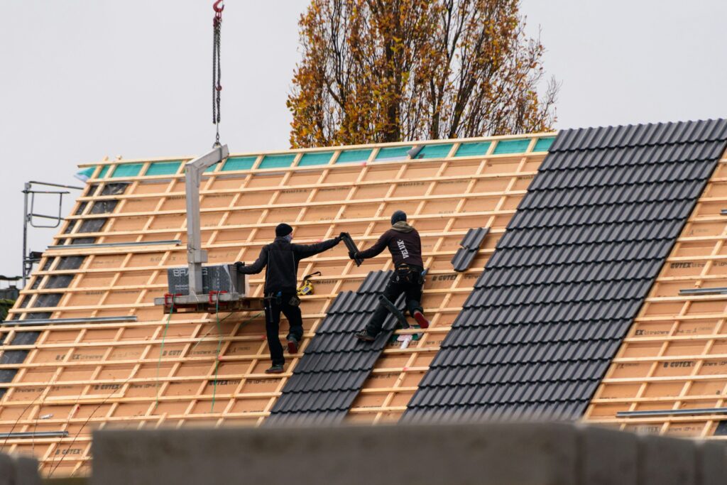 Roofers working on a dark tile roof installation over battens Roofers working on a dark tile roof installation over battens