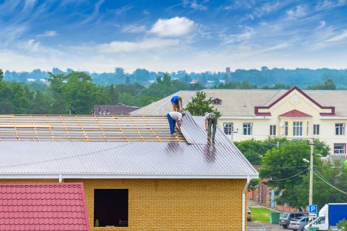 Roofers working on the flat roof of a building under construction