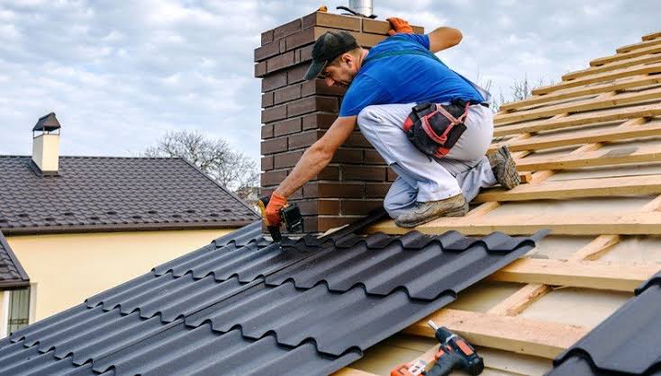 Roofer repairing shingles on a roof