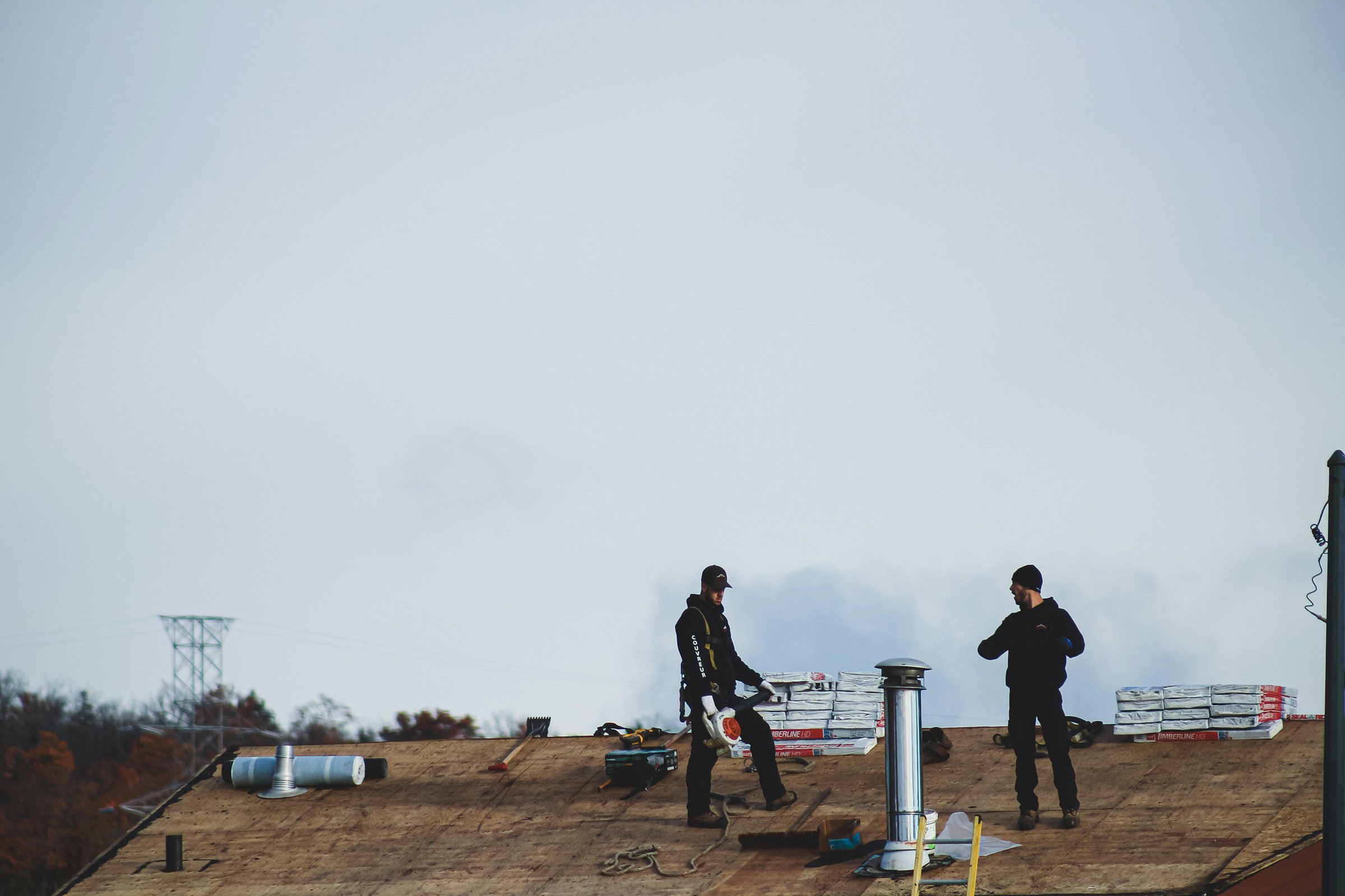 Roofers working on a flat commercial roof on a cloudy day Roofers working on a flat commercial roof on a cloudy day