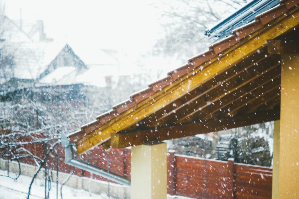 Snow falling on a covered porch roof and eaves in winter Snow falling on a covered porch roof and eaves in winter