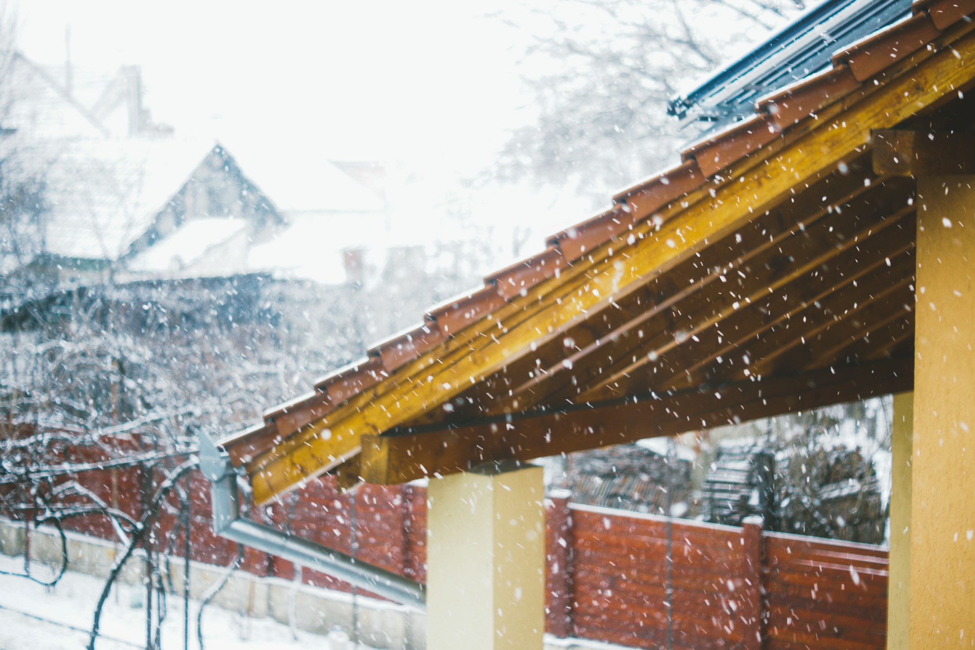 Snow falling on a covered porch roof and eaves in winter