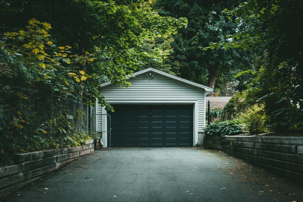 Detached garage with a gable roof at the end of a tree-lined driveway Detached garage with a gable roof at the end of a tree-lined driveway