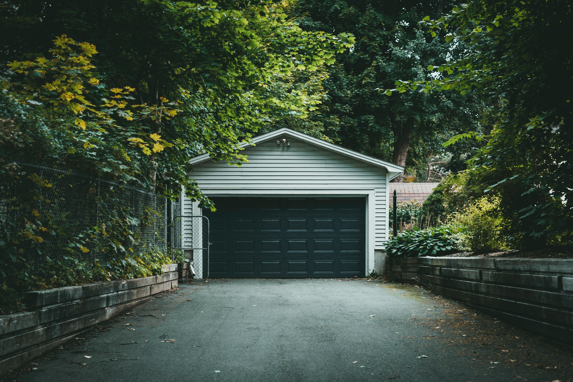 Detached garage with a gable roof at the end of a tree-lined driveway