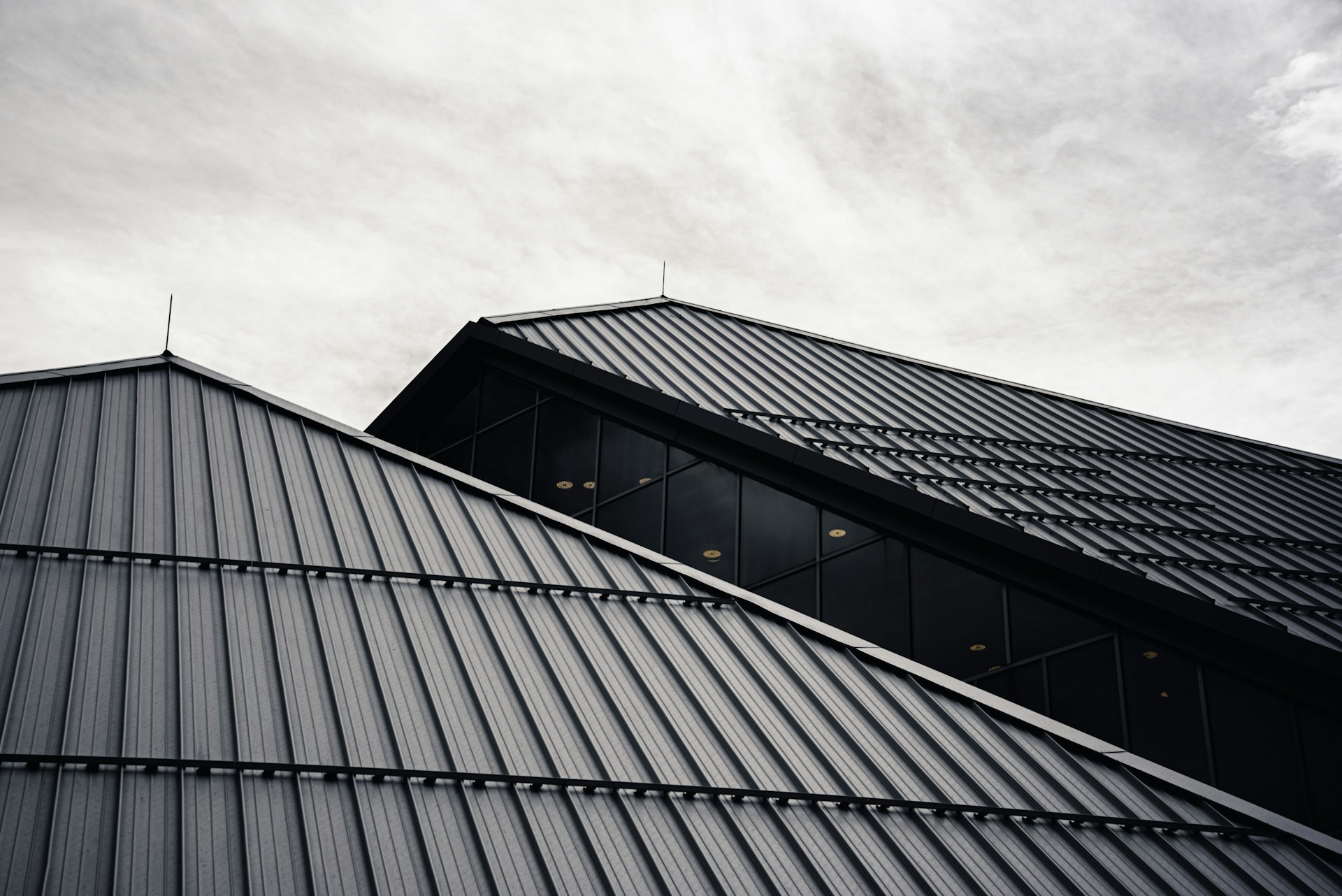 Dark standing seam metal roofs against a cloudy sky