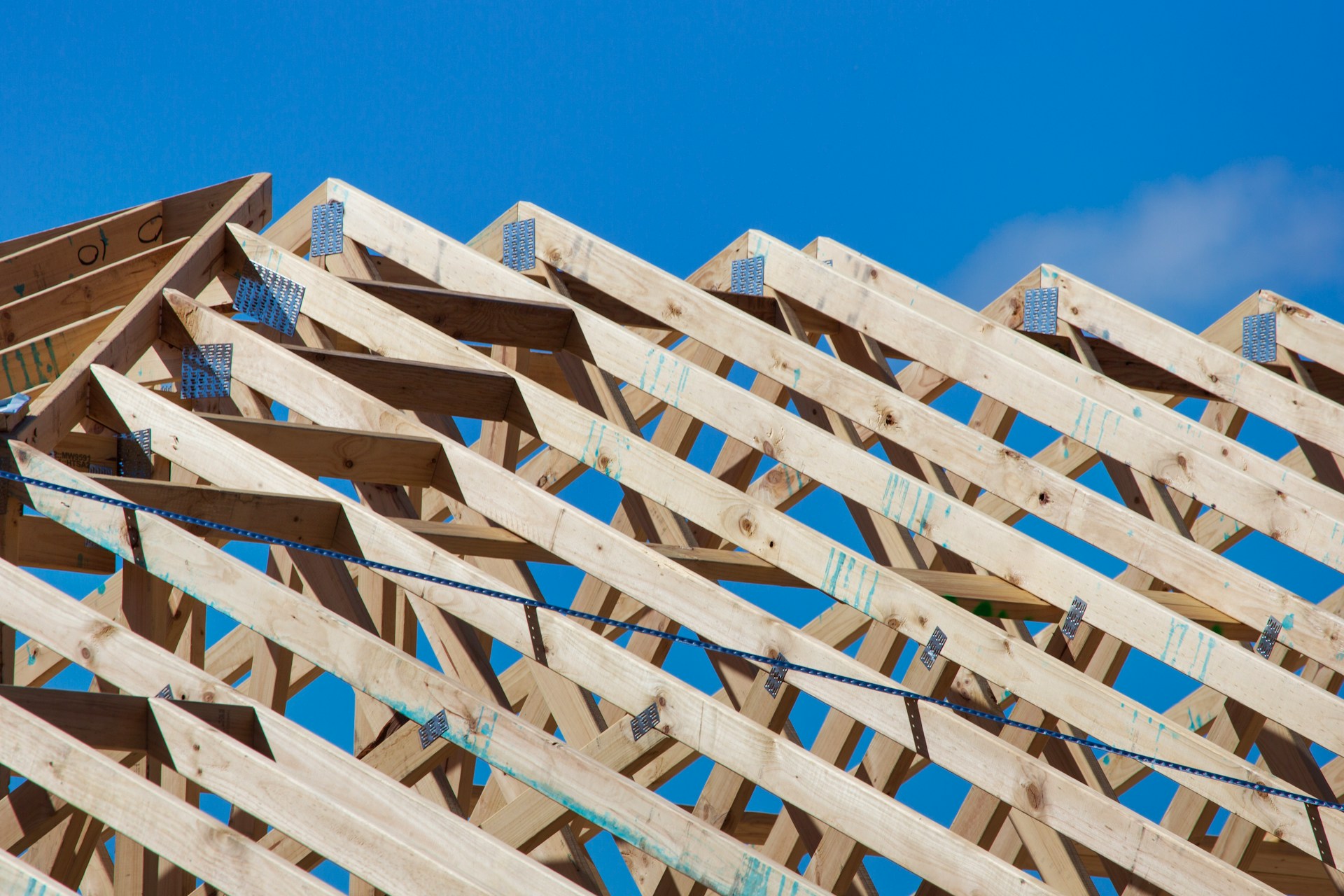 Wooden roof trusses framed against a clear blue sky